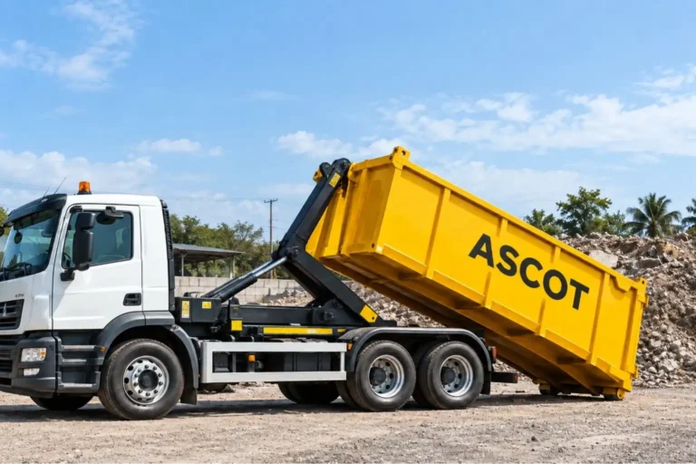 Ascot hook loader lorry lowering a yellow roro skip onto a hardstanding yard